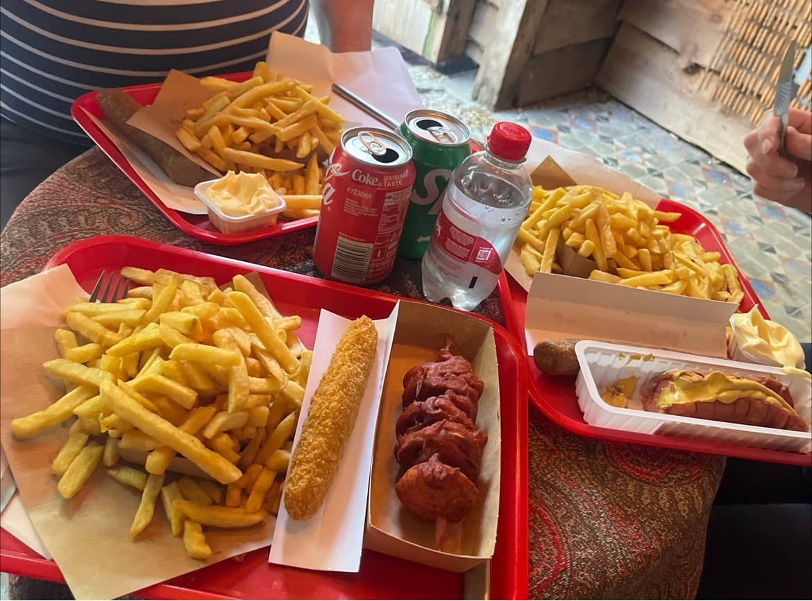Meerdere rode dienbladen vol friet en snacks naast elkaar