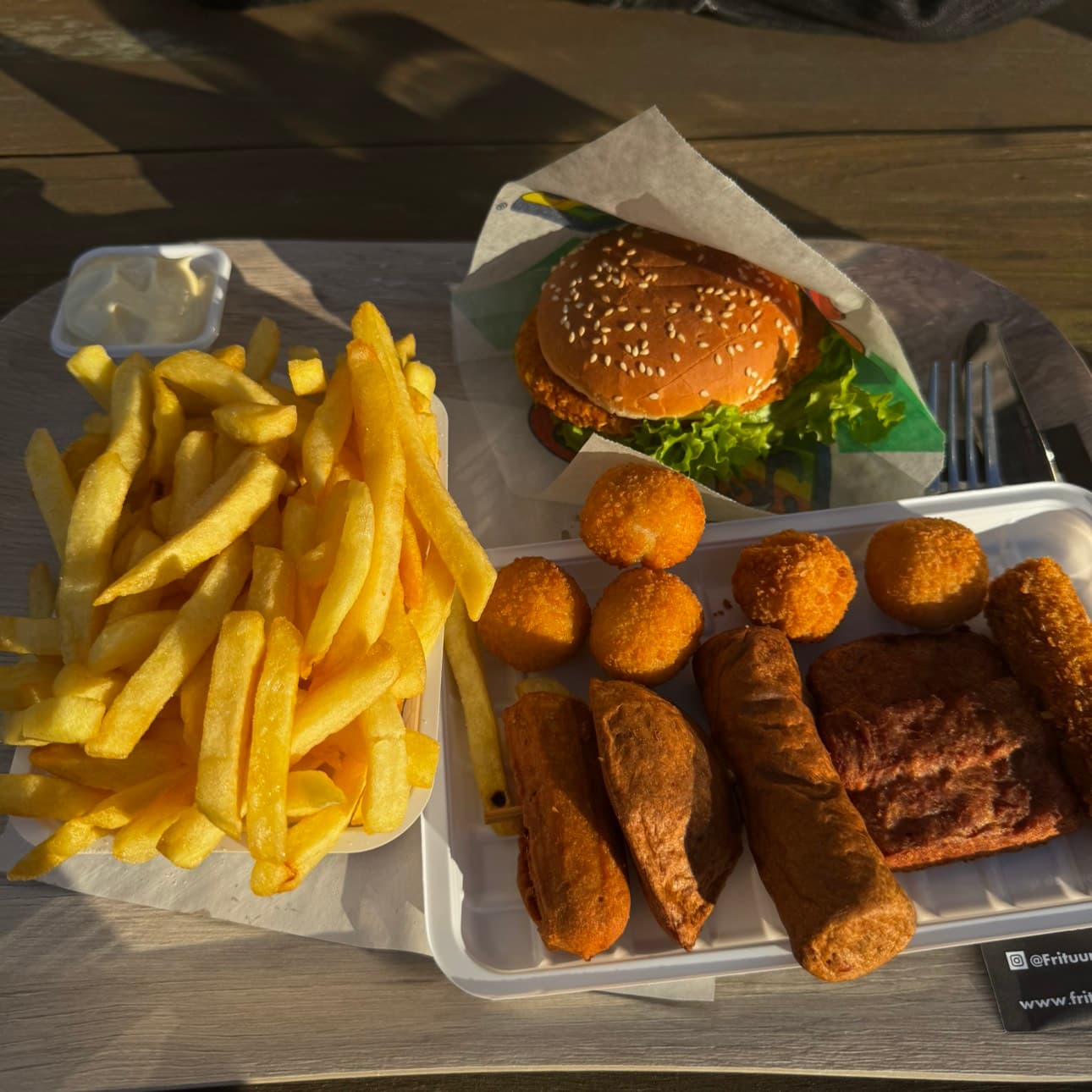 Friet met burger en snacks buiten op een terras in de zon